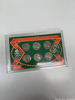 Seven 5 cent coins with Indian Head and Buffalo designs displayed in a green card holder in a plastic case.