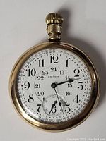 Full front view of gold-filled Waltham pocket watch showing white dial with 12-hour and 24-hour markings and subsidiary seconds.