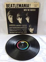 Black vinyl record with Capitol label in center, placed before its sleeve cover.