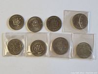 All eight different Canadian special issue dollar coins arranged in two rows, with some coins in protective sleeves.