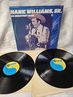 Photo of two vinyl LP records with MGM Records labels and outer cover featuring Hank Williams Sr 24 Greatest Hits title.