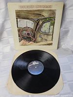 Photo of the vinyl record partially removed from the cover, showing the record label and part of the album jacket illustrating a car interior.