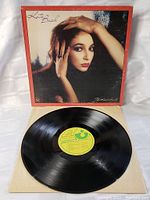 Front view of album cover sleeve with Kate Bush portrait and red border. Vinyl record partially visible inside cover.