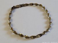 Full view of the circular sterling silver twisted design bracelet laid flat on a white surface showing its classic vintage pattern and clasp.