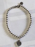 Full view of silver bead bracelet laid flat on fabric background