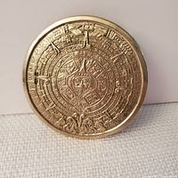 Front of round belt buckle showing detailed Aztec sun calendar design in relief