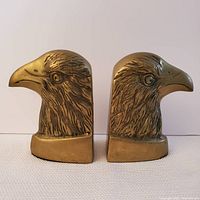 Front view of the brass eagle head bookends showing detailed feather and beak engravings.