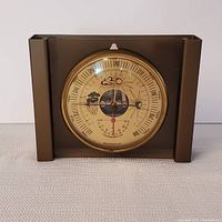 Full view of the barometer and thermometer instrument showing the smoked plexiglass and bronze frame with central dial.
