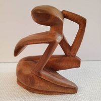 Front and side view showing abstract seated figure with arm resting on raised knee, smooth wood grain visible