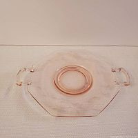 Top view of pink depression glass plate with octagonal shape, two handles, and etched floral design.
