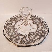 Full view of the glass serving plate featuring a clear glass sculpted handle and silver deposit pattern of oak leaves and acorns.