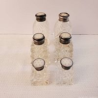 Photo showing all six salt and pepper shakers arranged in two rows, highlighting different sizes and the sterling silver tops.