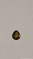 Top and side views of a natural olive green yellow pear cut tourmaline gemstone 9x7mm on plain background.