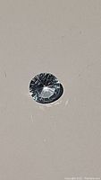 Photo of round sky blue topaz with fancy concave cut showing intricate light refractions on surface.