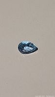 Close-up image of the pear-shaped sky blue topaz gemstone showing its concave facets and clarity.