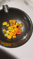 Overhead close-up photo of multiple polished orange fire opal stones in a black container showing multicolored flash.