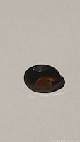 Top view of the oval cut garnet showing deep cognac color and facets reflecting light.