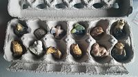 Twelve Wade porcelain animal figurines arranged in an egg carton, showing various crafted animals with detailed painting in good condition.