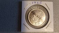 Front side of the 1965 Canadian silver 50 cent coin showing the Canadian coat of arms and denomination.