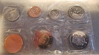 View of first uncirculated coin set in sealed plastic packaging showing seven Canadian coins including a large commemorative coin