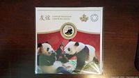 Front view of the coin's display card featuring panda images and gold-accented coin with panda motif