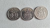 Reverse sides of three Canadian 50 cent coins featuring the Canadian coat of arms and the denomination.