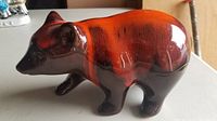 Single ceramic bear figurine with glossy orange and brown glaze, shown side view on flat surface.