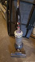 Front view of Dyson upright vacuum cleaner showing handle, dustbin and motorized brush head attached.