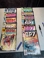 Image of the 11 vintage comic books arranged vertically showing titles including Spitfire, Kickers Inc., Merc, Nightmask, Ps Force, and DP7. Includes a pen and ruler for scale.