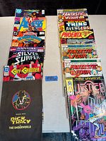 Photo of 12 vintage comic books arranged on a table. Covers include Silver Surfer, Guy Gardner, Dick Tracy, several Fantastic Four issues, Avengers, Phoenix, Justice, and New Universe titles.