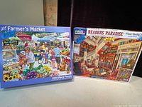 Photo showing two puzzle boxes: White Mountain brand puzzles, titled "Farmer's Market" and "Readers Paradise" each containing 1000 pieces.