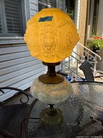 Full view of the Victorian style oil lamp converted to electric, showing lit frosted glass lion face shade and ornate base.