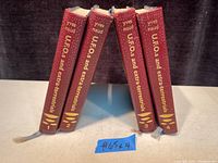 Photo showing the spines of 4 volumes with maroon color, numbered 1 to 4, with titles and author names in gold embossing.