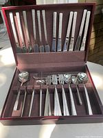 Open oak box showing textured-handle cutlery set arranged in fitted compartments