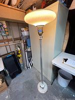 Full view of lit floor lamp showing shade, column, and base