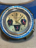 Watch face showing gold-tone dial, black subdials, blue and white rotating bezel