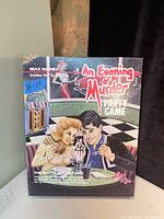 Box of the vintage 1989 An Evening of Murder party game Last Kiss edition showing illustrated cover with couple at diner counter and jukebox.