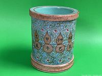 Front view of cloisonné rotating pen holder showing calendar ring and floral enamel design