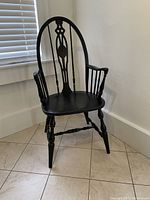 Front three-quarter view of the chair showing arched back, armrests, contoured seat and turned legs