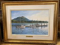 Full view of framed oil painting showing mountain backdrop, docked boats and title plaque