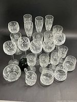 Overview of 18-piece crystal stemware and tumblers set arranged behind green apple