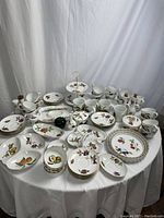 Overview of entire set on white tablecloth showing assorted plates, cups, mugs, and serveware