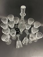 Overhead view of decanter with stopper surrounded by multiple crystal stemware glasses arranged in semicircle