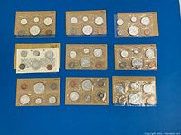 Nine sealed coin sets arranged in three rows of three on blue background