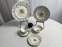 Overview of single place setting with various plate sizes, teacup, saucer and double-handled cup alongside scale reference