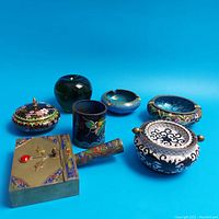 Overview of all six Asian cloisonne objects, showing variety of shapes and designs including ashtrays, jars, and lidded boxes.
