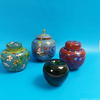 Photo showing all three lidded jars with the green apple for size reference, multiple colors and styles visible.