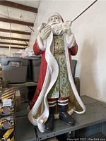 Full view of a vintage 3-foot tall Santa Claus fiberglass blow mold with detailed red coat and green robe with gold accents, holding a scroll and quill