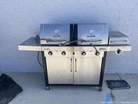 Front view of full Char Broil Commercial Series grill with dual lids and side burner, showing temperature gauges on lids and cabinet storage below.