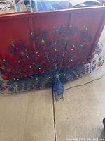 Photo of large metal peacock sculpture with spread tail and colored lights
